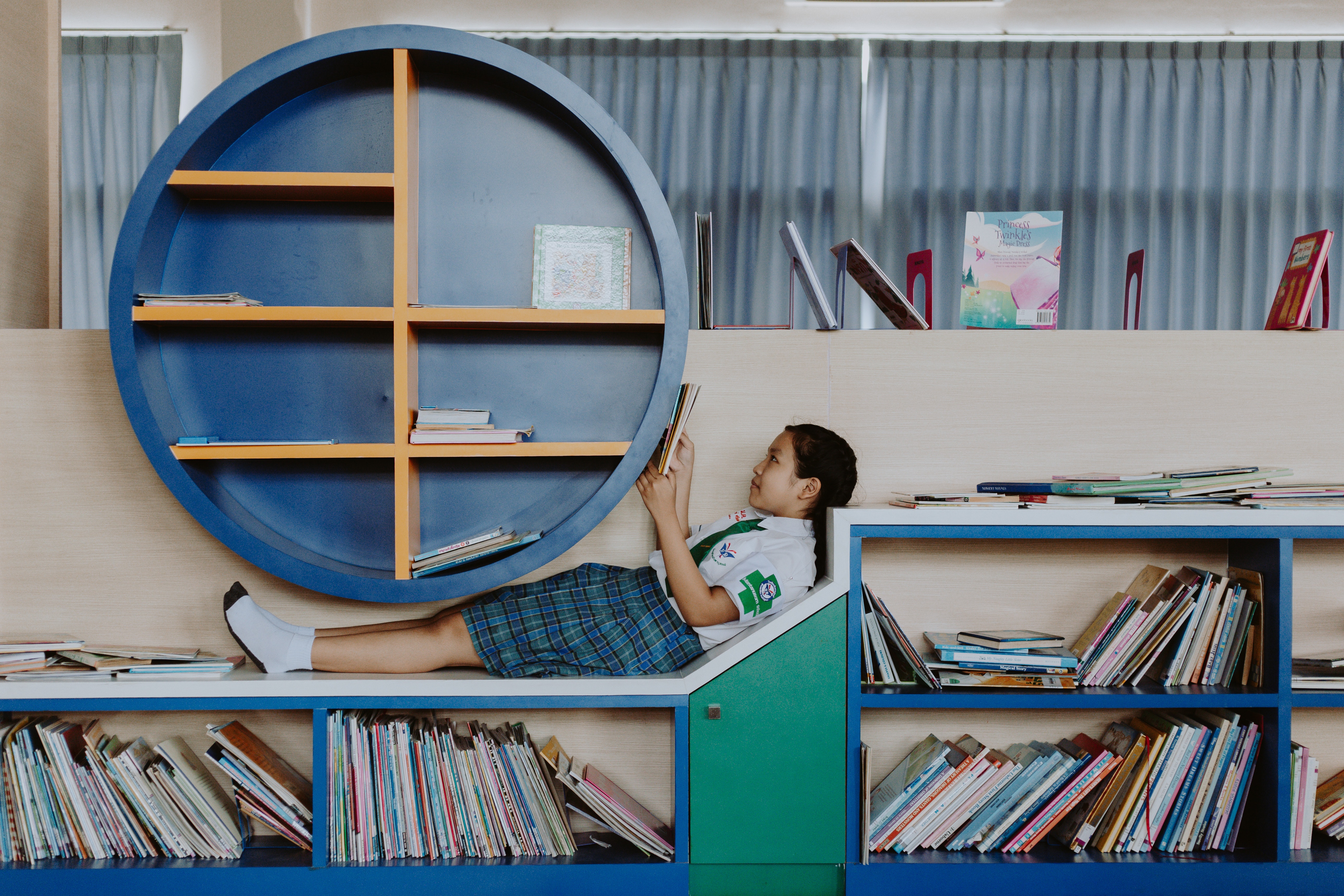 photo by ron lach : https://www.pexels.com/photo/girl-in-school-uniform-lying-on-book-shelf-and-reading-10638226/