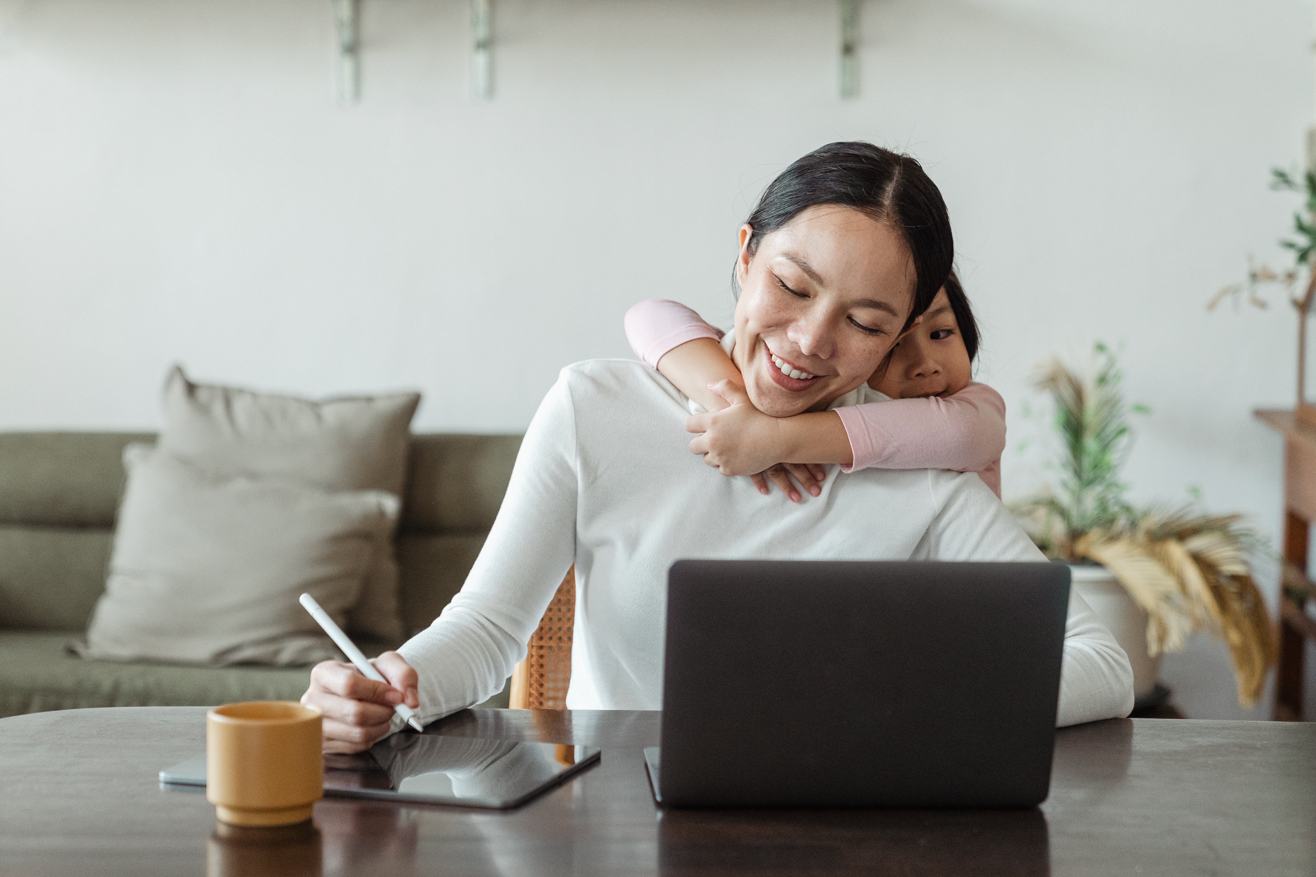 a mother working or doing hobby with her daughter hugging her